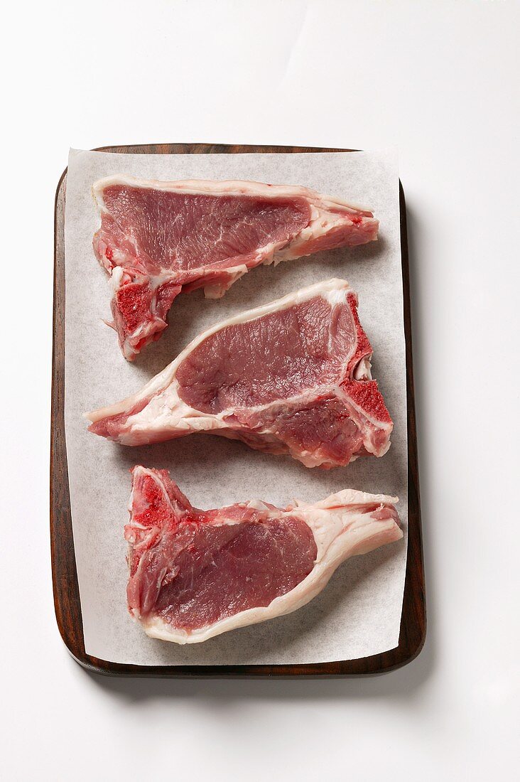 Three lamb cutlets on paper on chopping board