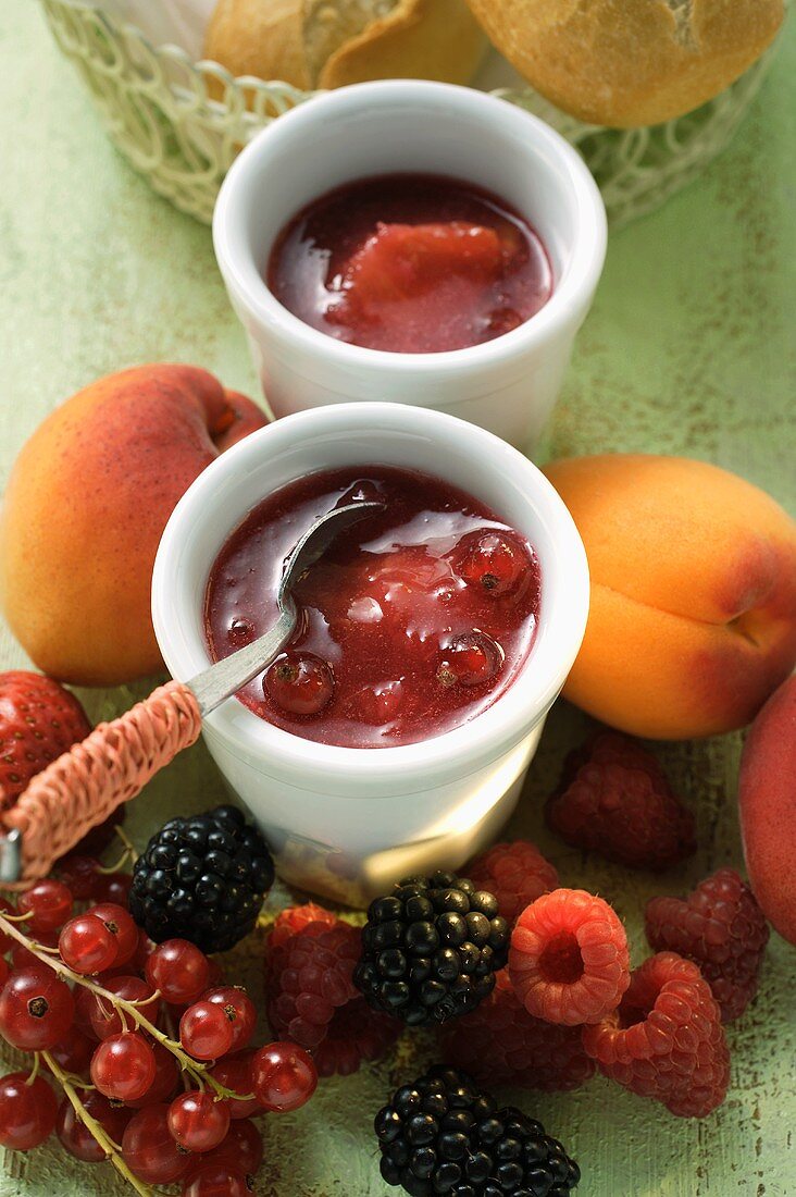 Mixed-fruit jam in small bowl, surrounded by fresh fruit