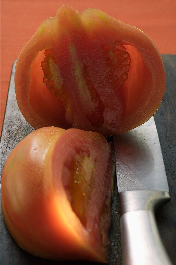 Halbe Tomate und Tomatenviertel auf Schneidebrett