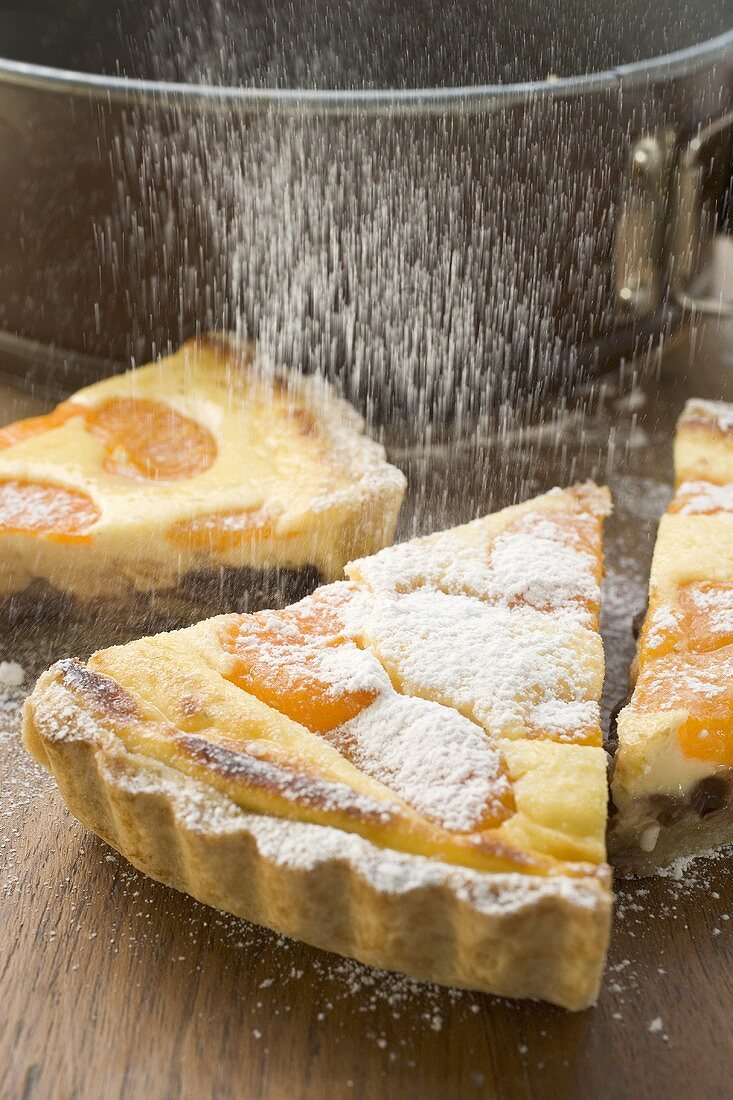 Sprinkling apricot tart with icing sugar