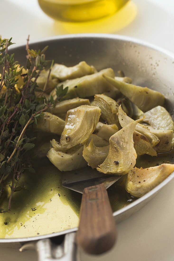 Frying artichokes with thyme in frying pan