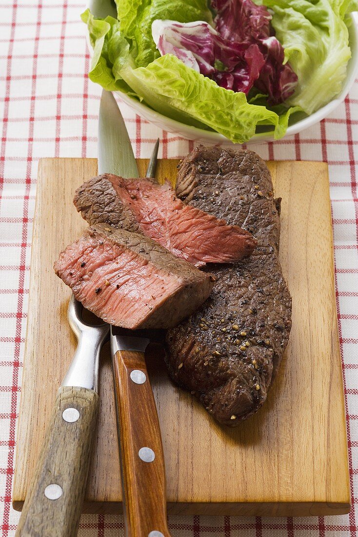 Beef steaks, partly sliced, salad