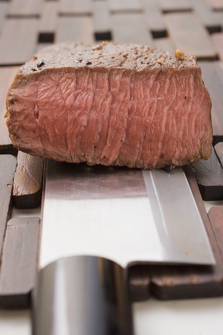 Beef steak, a piece cut off, on Asian knife