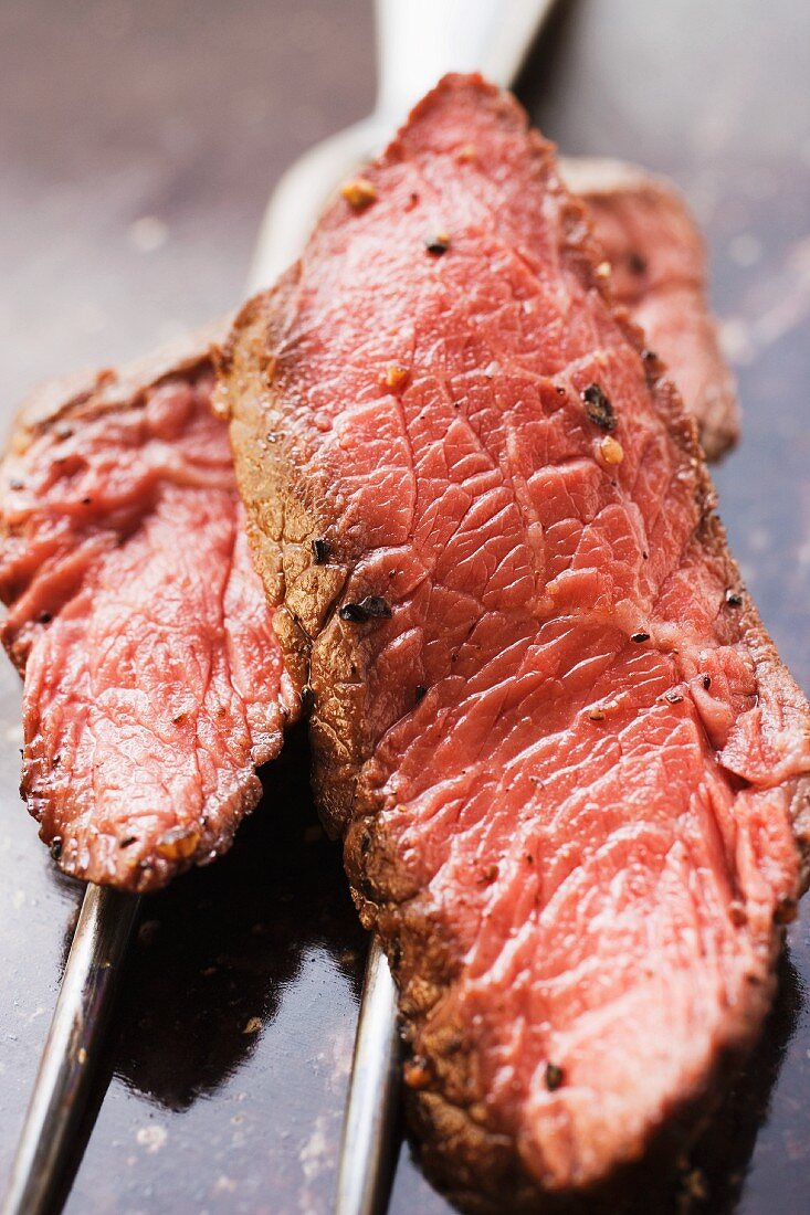 Two slices of beef steak on meat fork