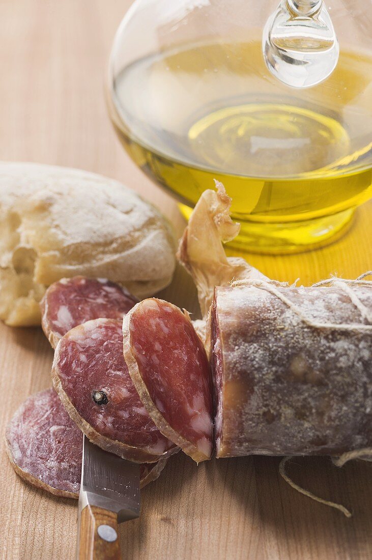 Italienische Salami, angeschnitten, Weißbrot, Olivenöl