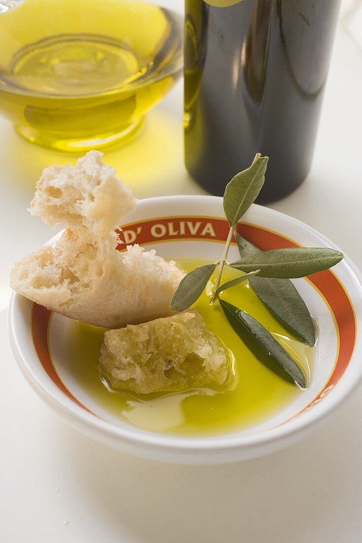 Olivenöl in Schale mit Weißbrot und Olivenzweig