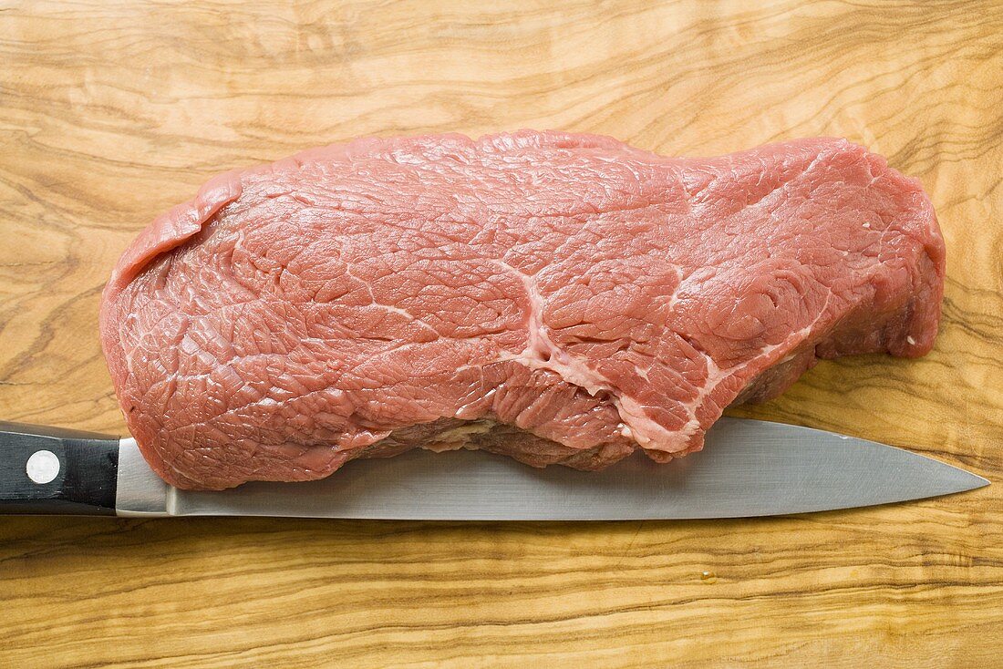 Beef sirloin with knife on chopping board