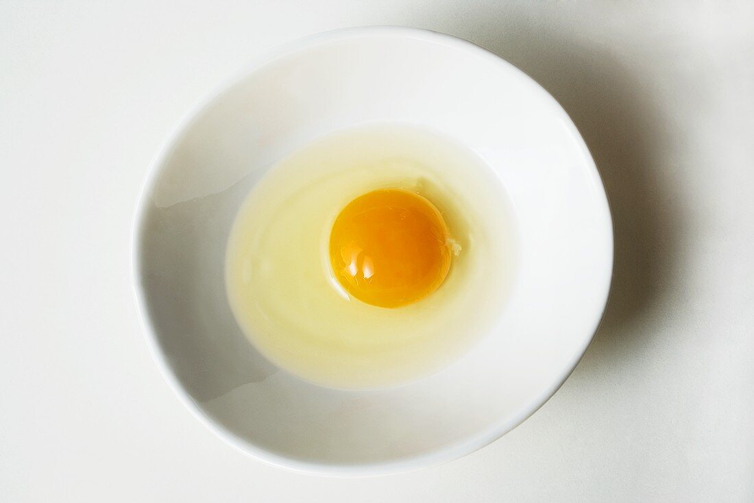 Aufgeschlagenes Ei in weißem Schälchen