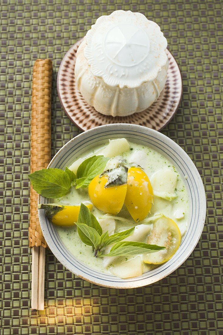 Coconut soup with potatoes, fish, Thai aubergines, basil