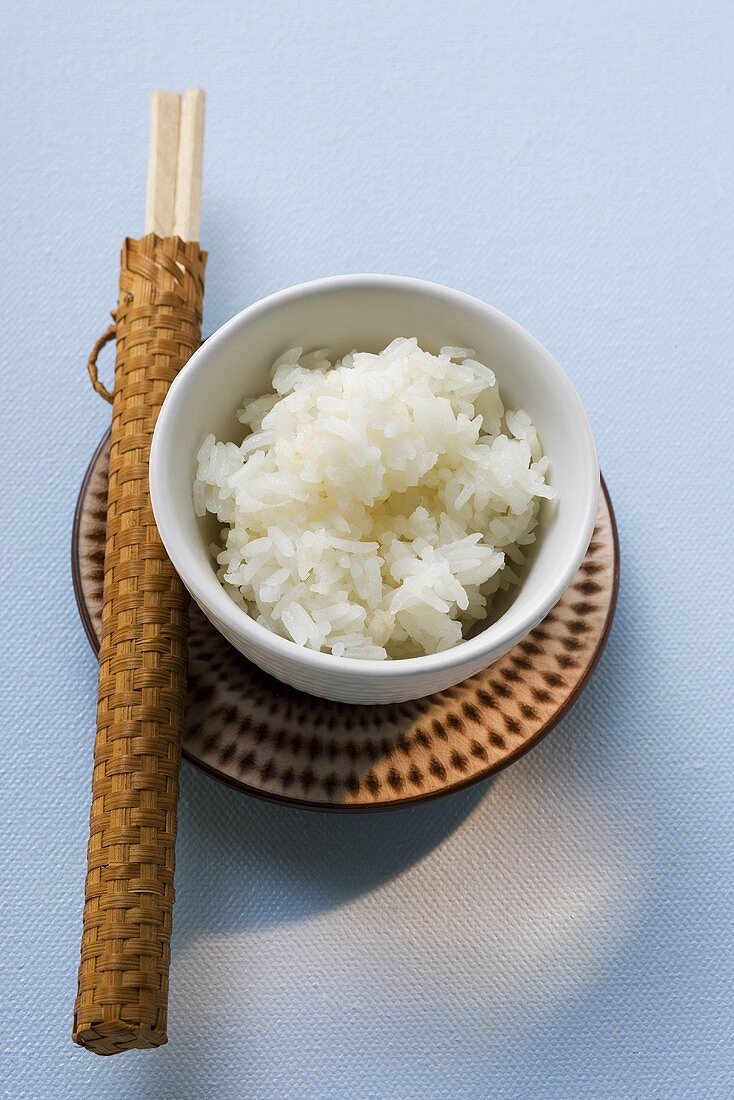 Bowl of rice and chopsticks on plate