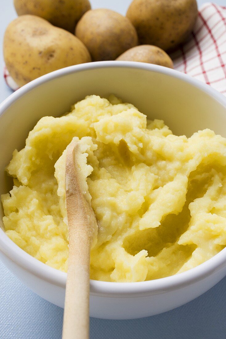 Mashed potato in bowl with wooden spoon