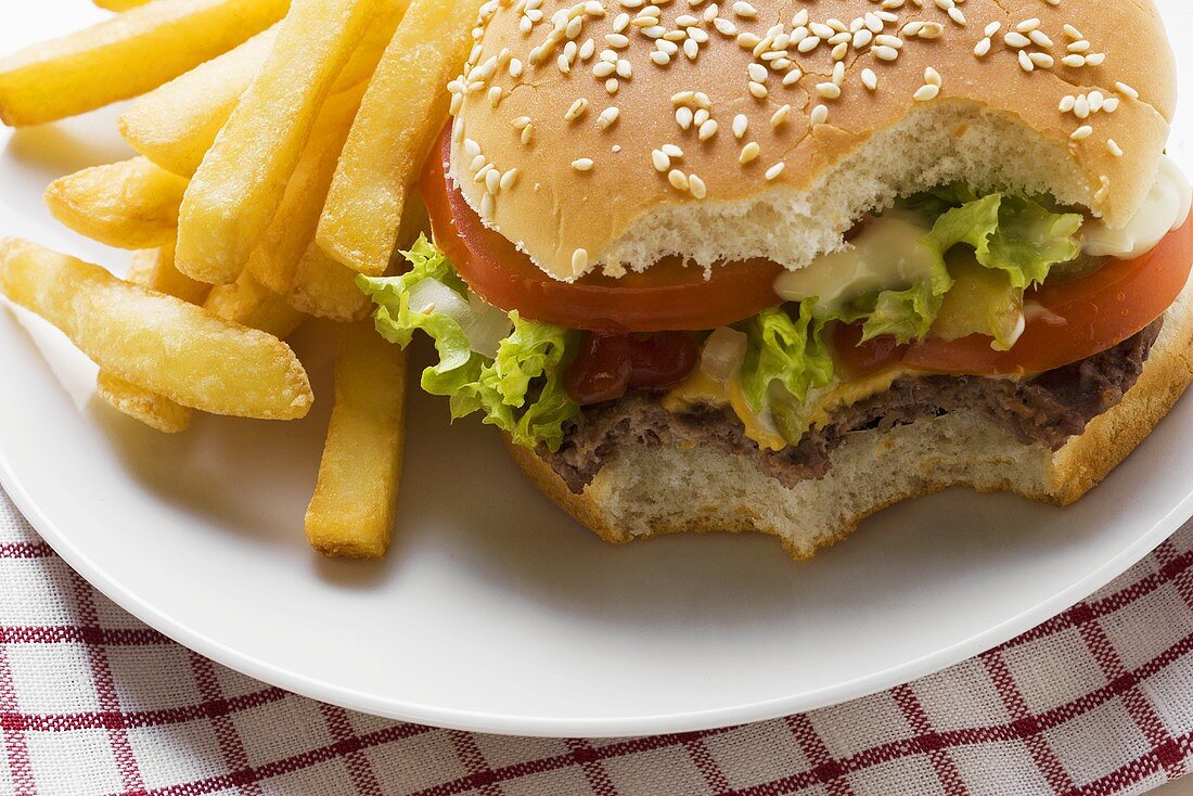 Cheeseburger, angebissen, mit Pommes frites