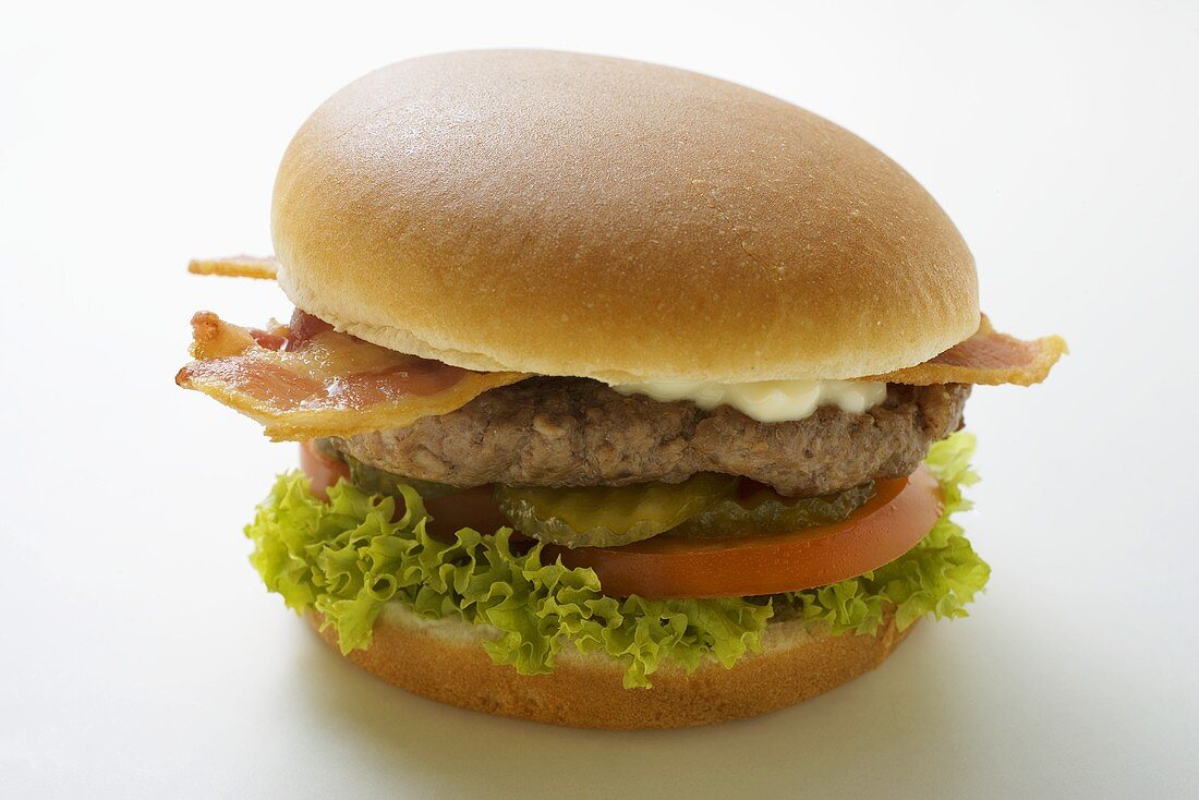 Hamburger with bacon, mayonnaise, gherkins, tomato, lettuce