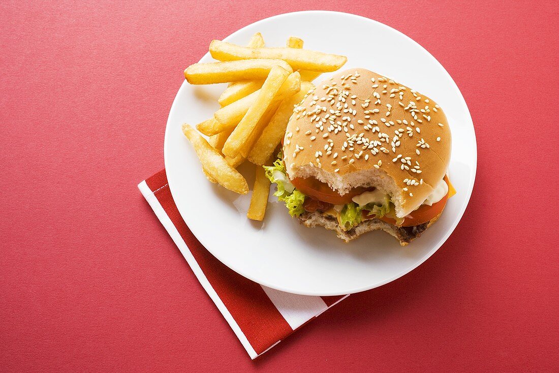 Cheeseburger, angebissen, mit Pommes frites