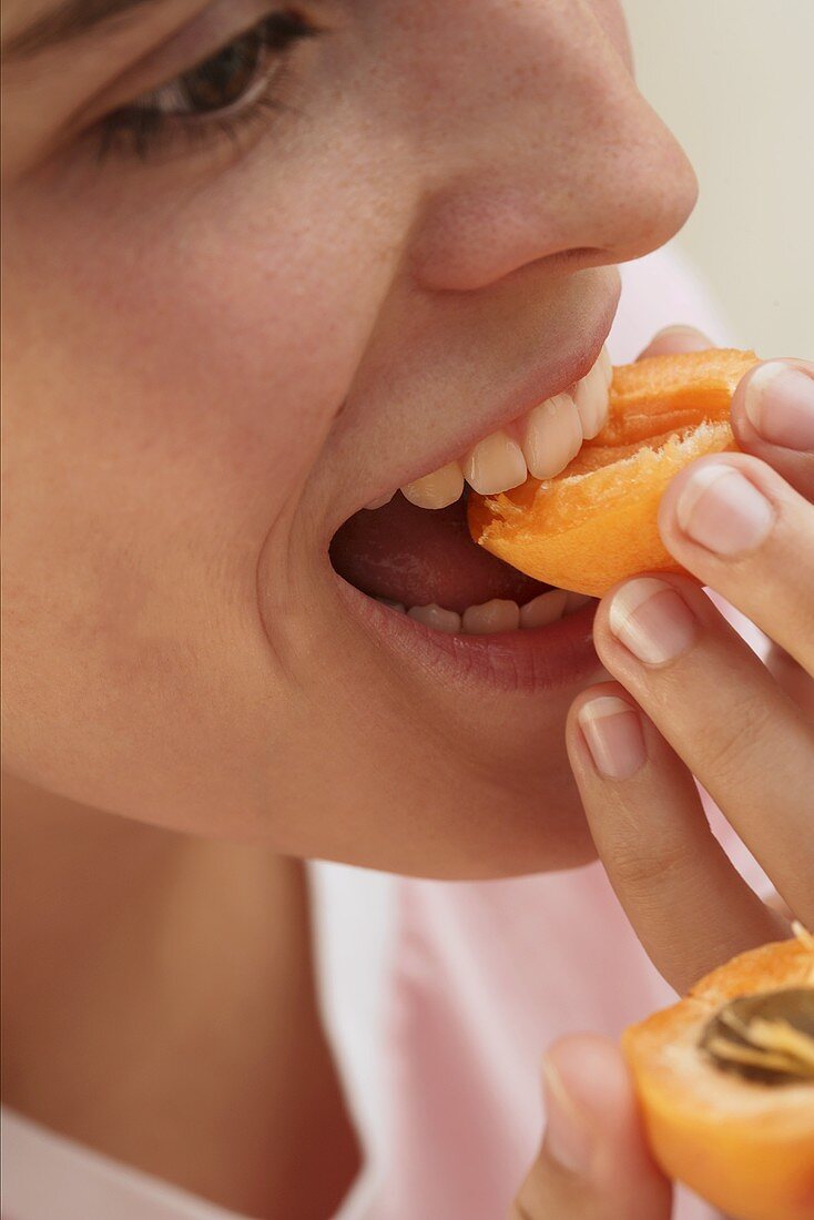 Woman biting into apricot