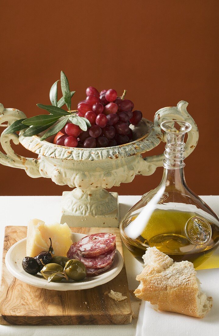 Oliven, Wurst, Parmesan, Brot, Olivenöl und rote Trauben