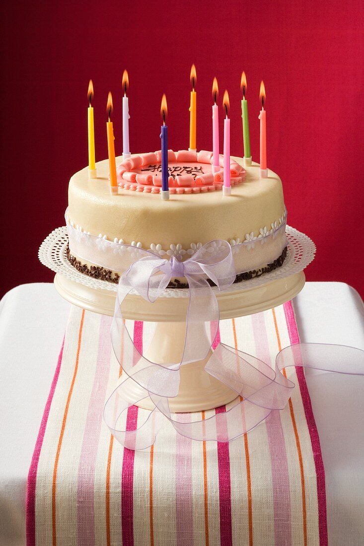 Birthday cake with burning candles on cake stand