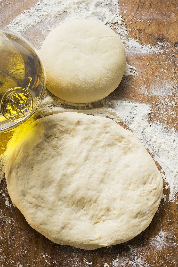 Uncooked dough, rolled out and in a ball, olive oil