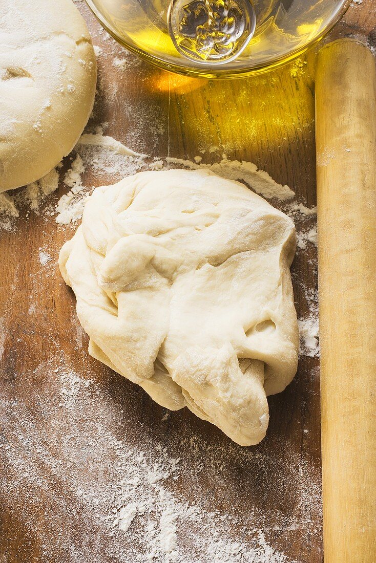 Dough, rolling pin, ball of dough and olive oil