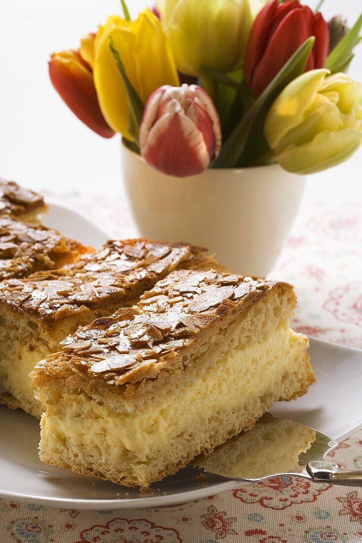 Mehrere Stücke Bienenstich auf Teller mit Kuchenheber