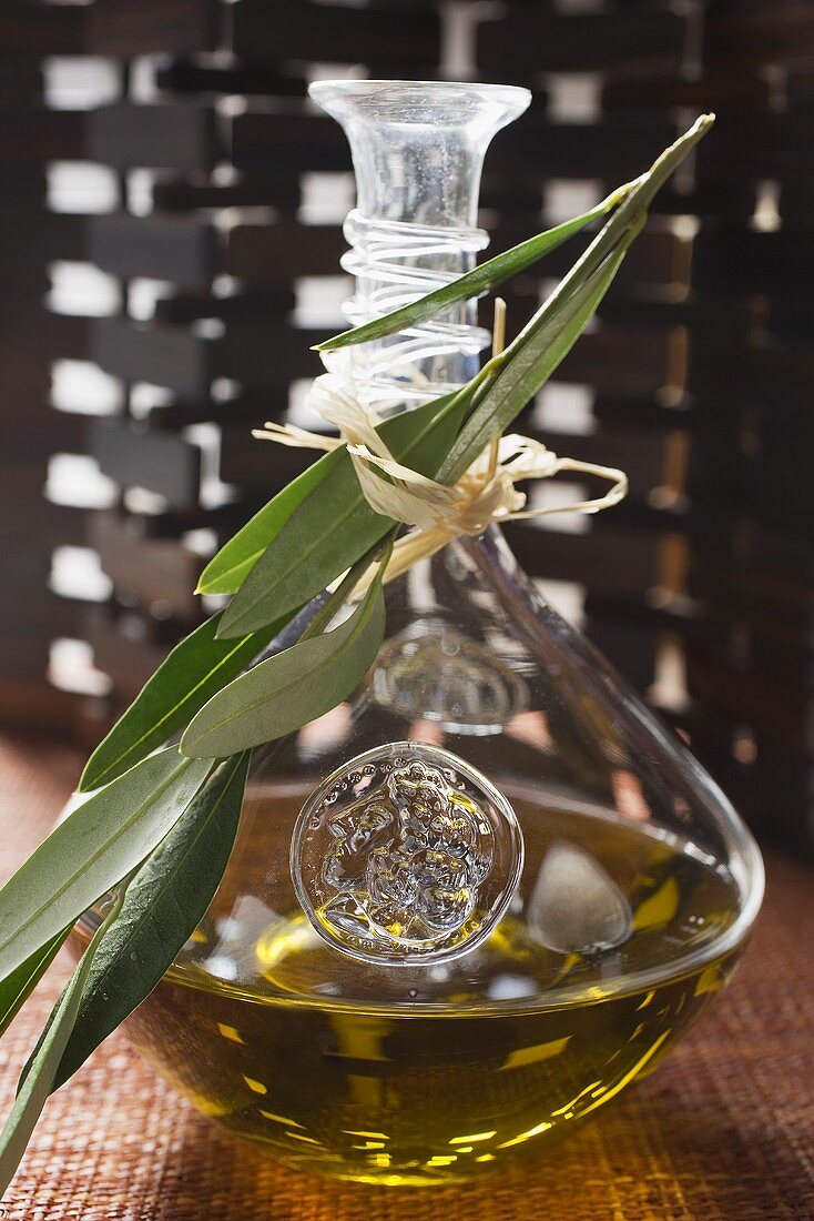 Olivenöl in Karaffe mit Olivenzweig