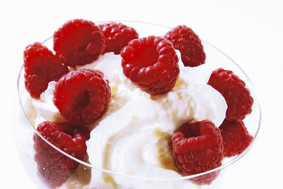 Fresh raspberries with cream in glass bowl