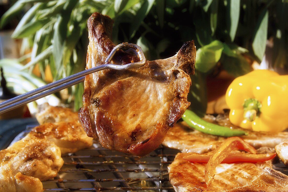 Grilled pork chop in grill tongs