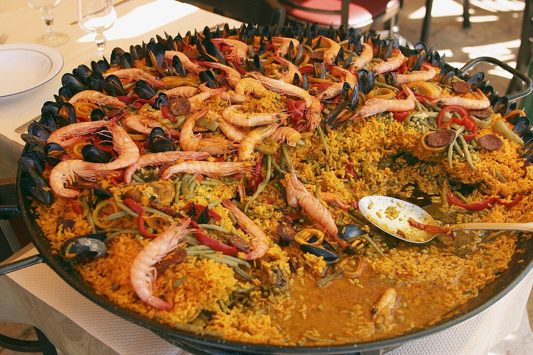 Paella in large frying pan on table in restaurant