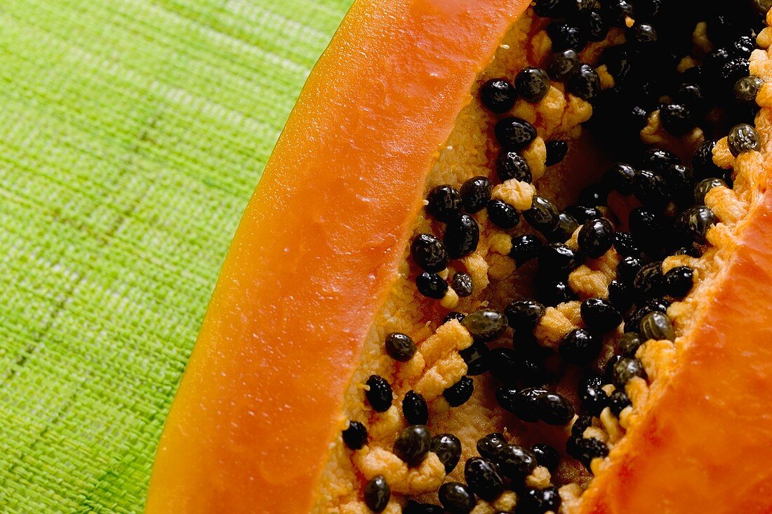 Half a papaya on green background