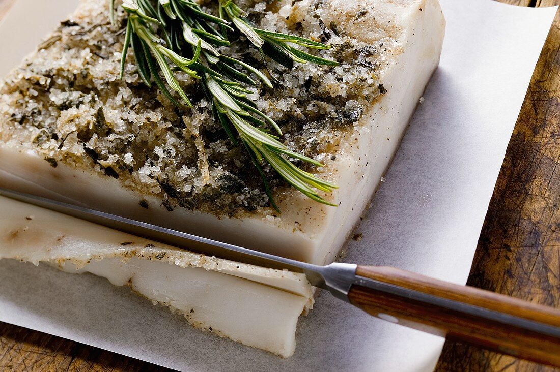 Bacon fat from Tuscany with rosemary, a slice being cut