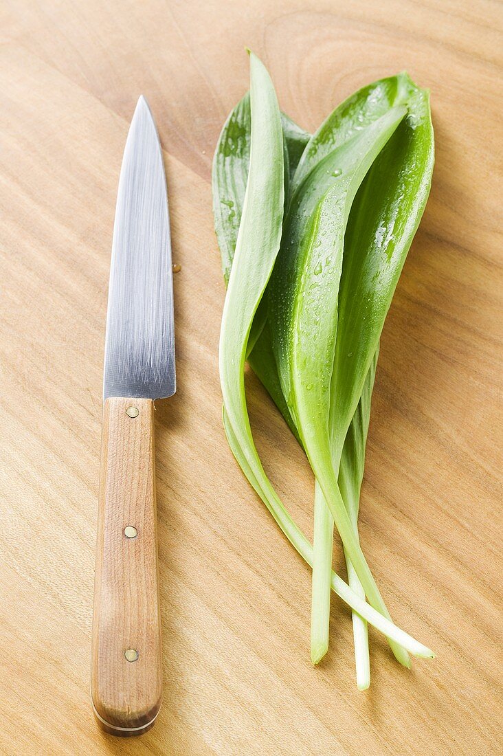 Fresh ramsons (wild garlic) on wooden background with knife