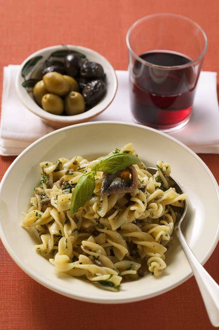 Fusilli mit Sardellen und Basilikum, Oliven, Glas Rotwein