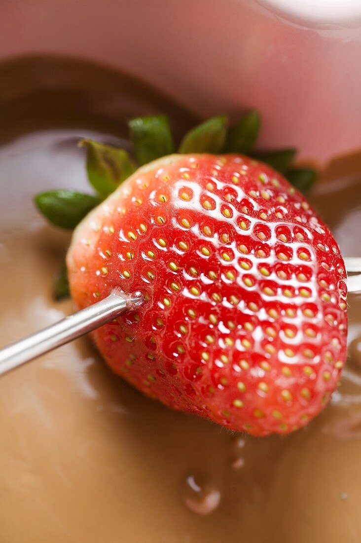 Chocolate fondue with strawberry on fondue fork