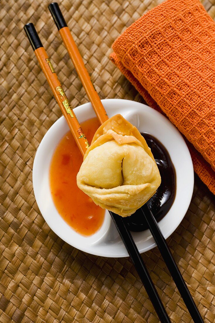 A deep-fried wonton with two sauces