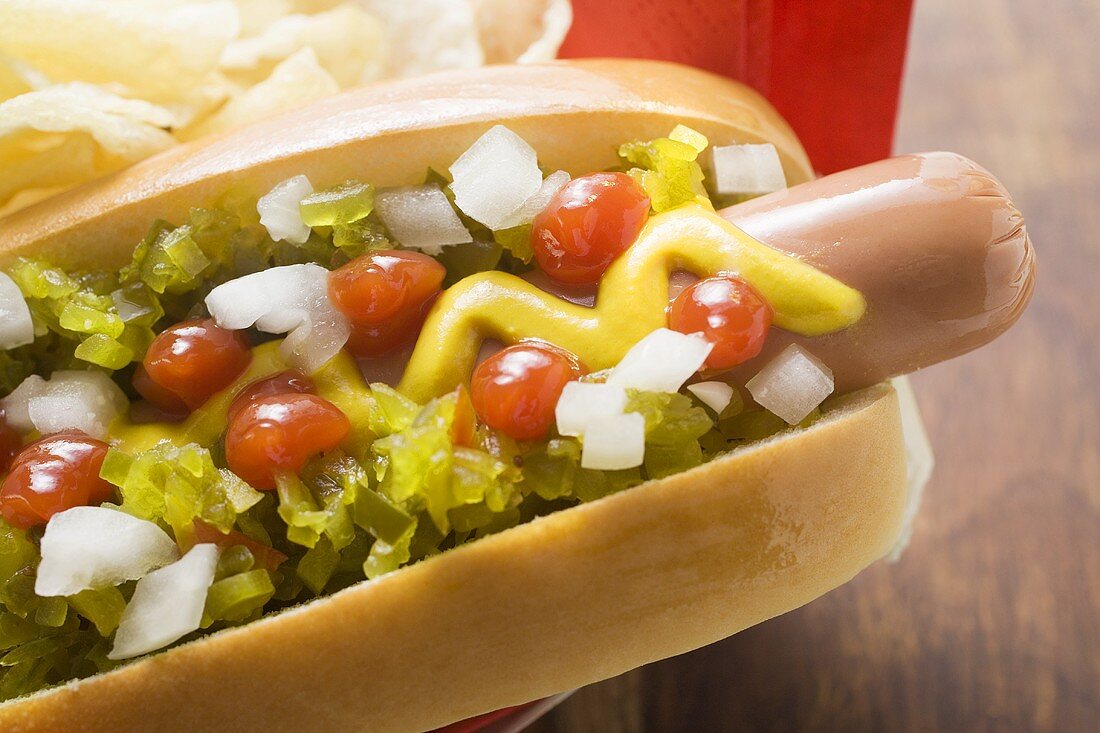 Hot dog with relish, mustard, ketchup, onions and crisps