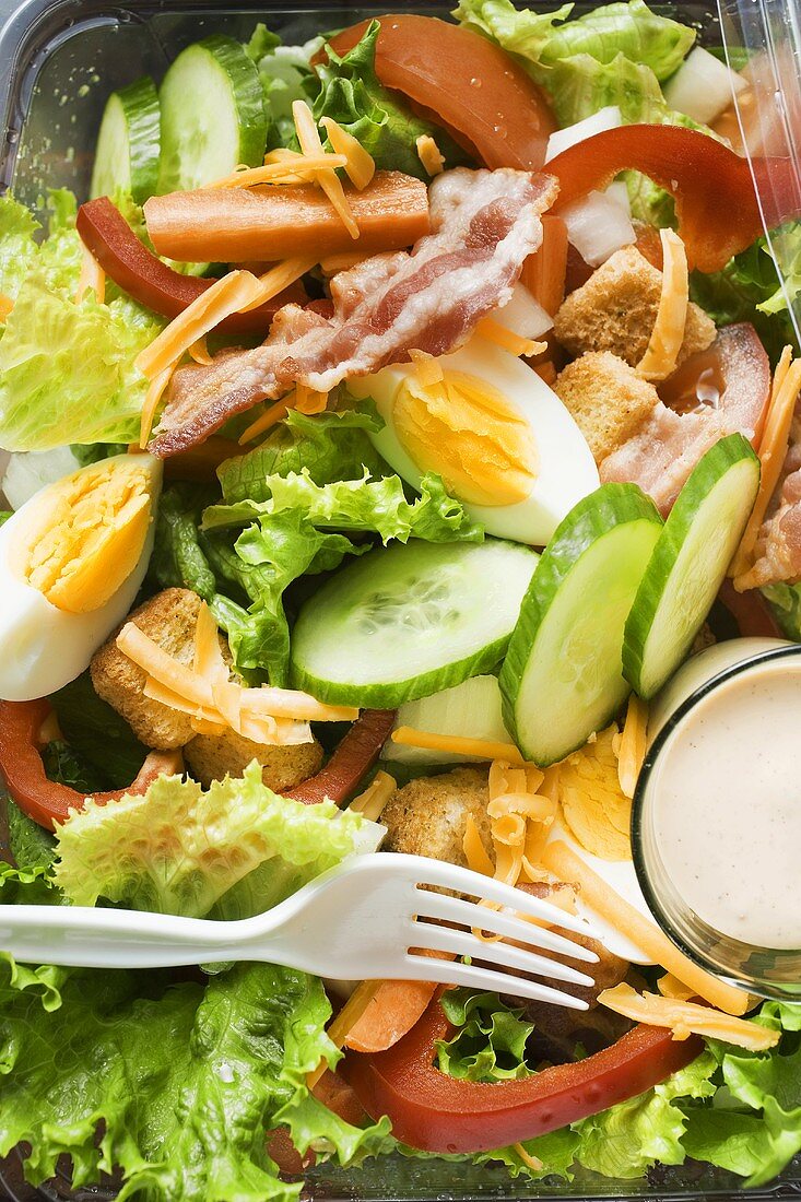 Blattsalat mit Ei, Käse, Bacon und Dressing zum Mitnehmen