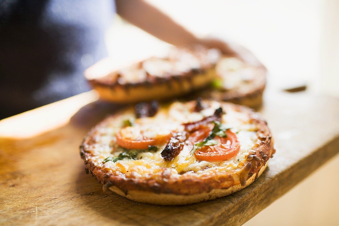 Person hält Holzbrett mit drei verschiedenen Minipizzen