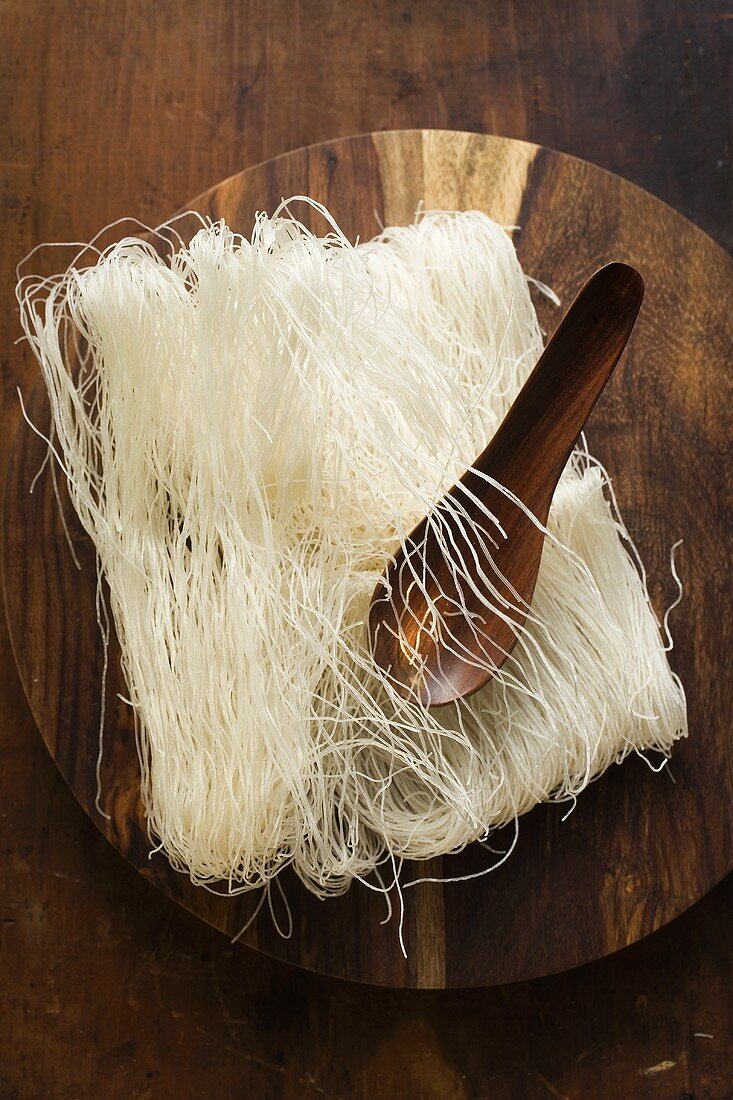 Thin rice noodles on wooden plate with spoon