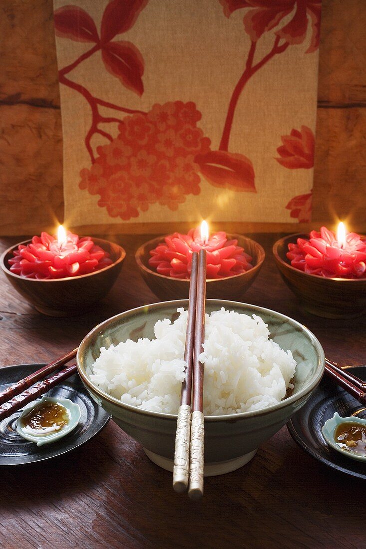 Schale Reis vor brennenden Kerzen (Thailand)