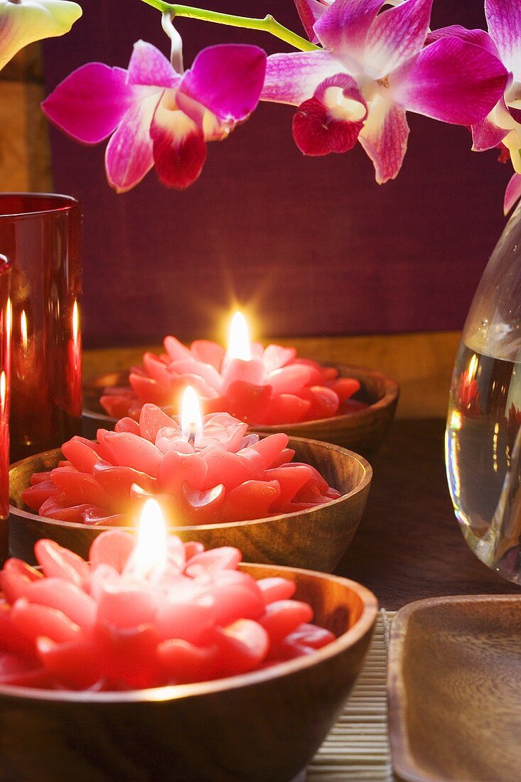 Thailändische Tischdeko: rote Blütenkerzen und Orchideen
