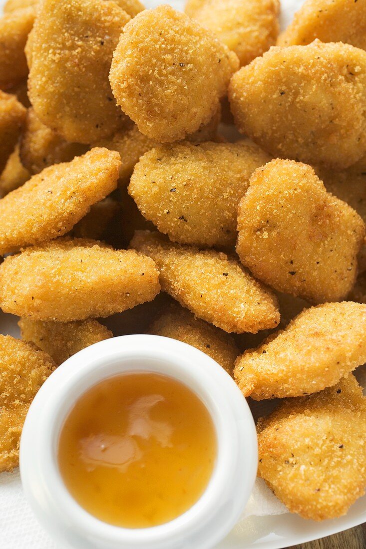 Many chicken nuggets with apricot sauce on plate