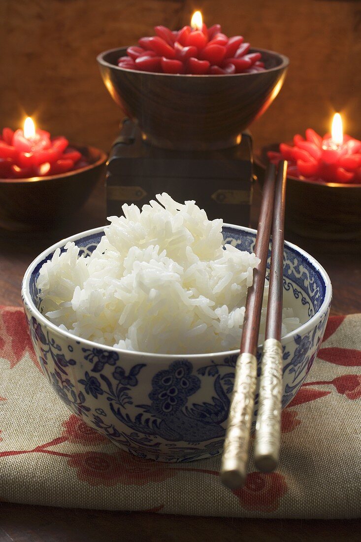Bowl of rice in front of burning candles (Asia)