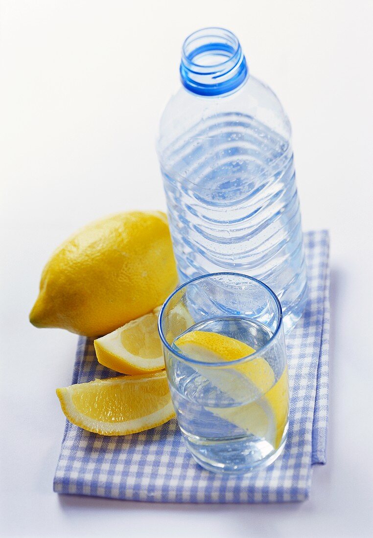 Mineralwasser in Flasche und Glas und Zitronenschnitze