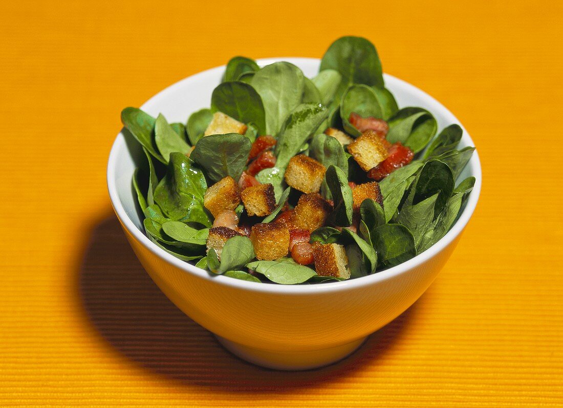 Corn salad with croutons and bacon in a small bowl