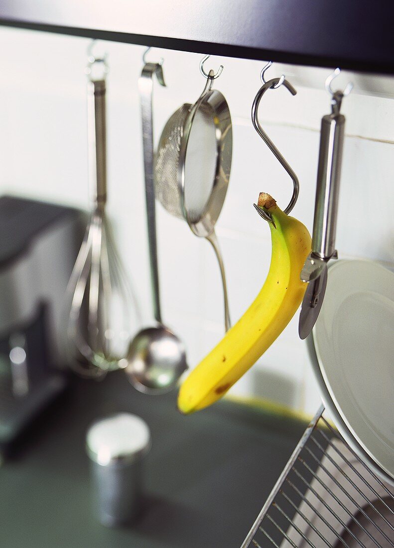 Banana and kitchen tools hanging on hooks in kitchen