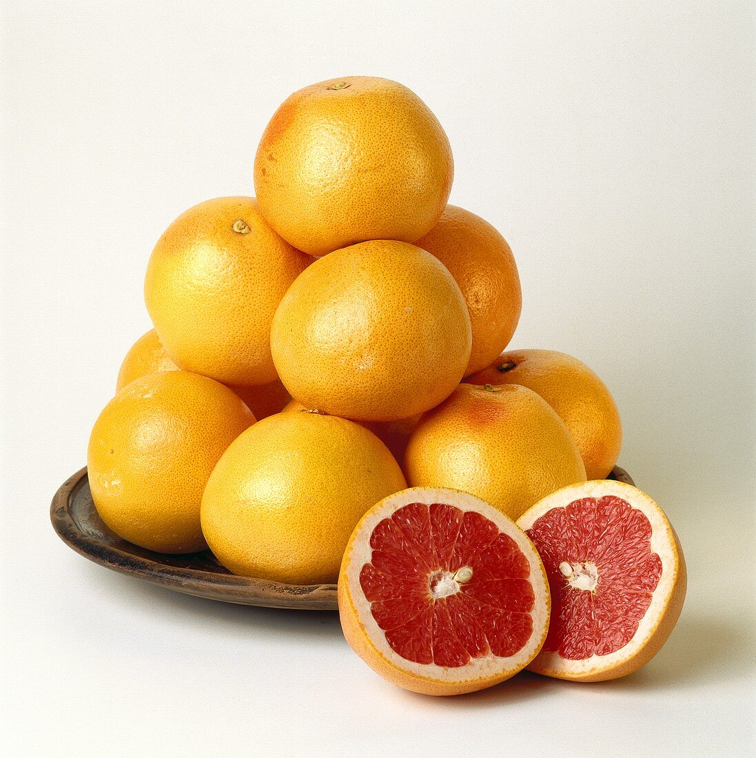 Pink grapefruits on plate, one cut open in front