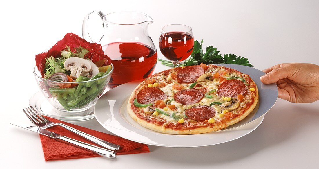 Salami pizza with salad and red wine