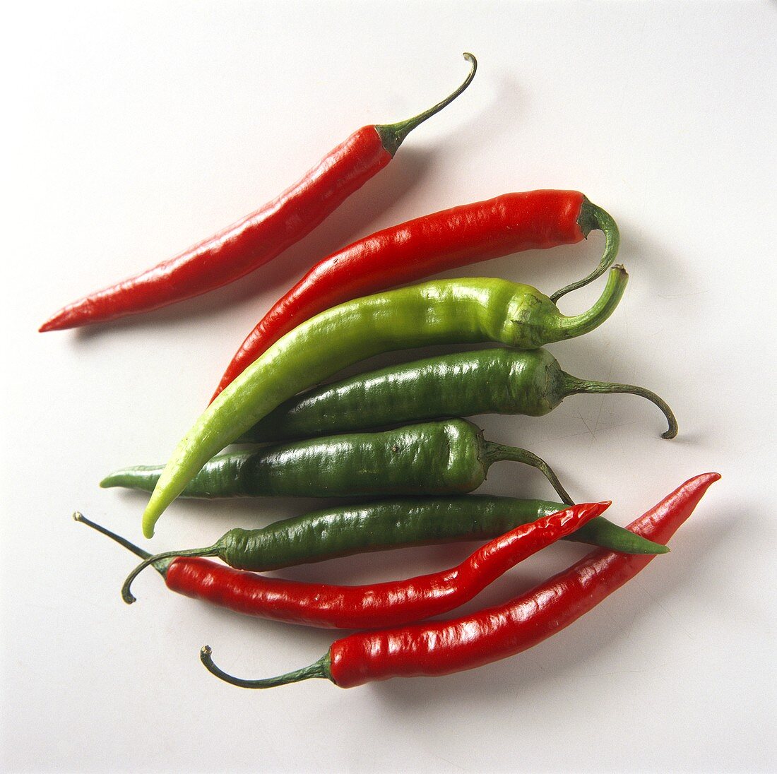 Four red and four green chili peppers on white background