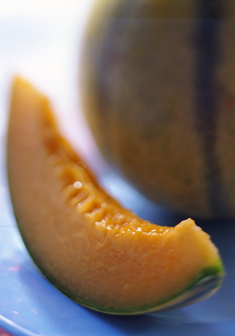 Slice of Cavaillon melon in front of whole melon on plate