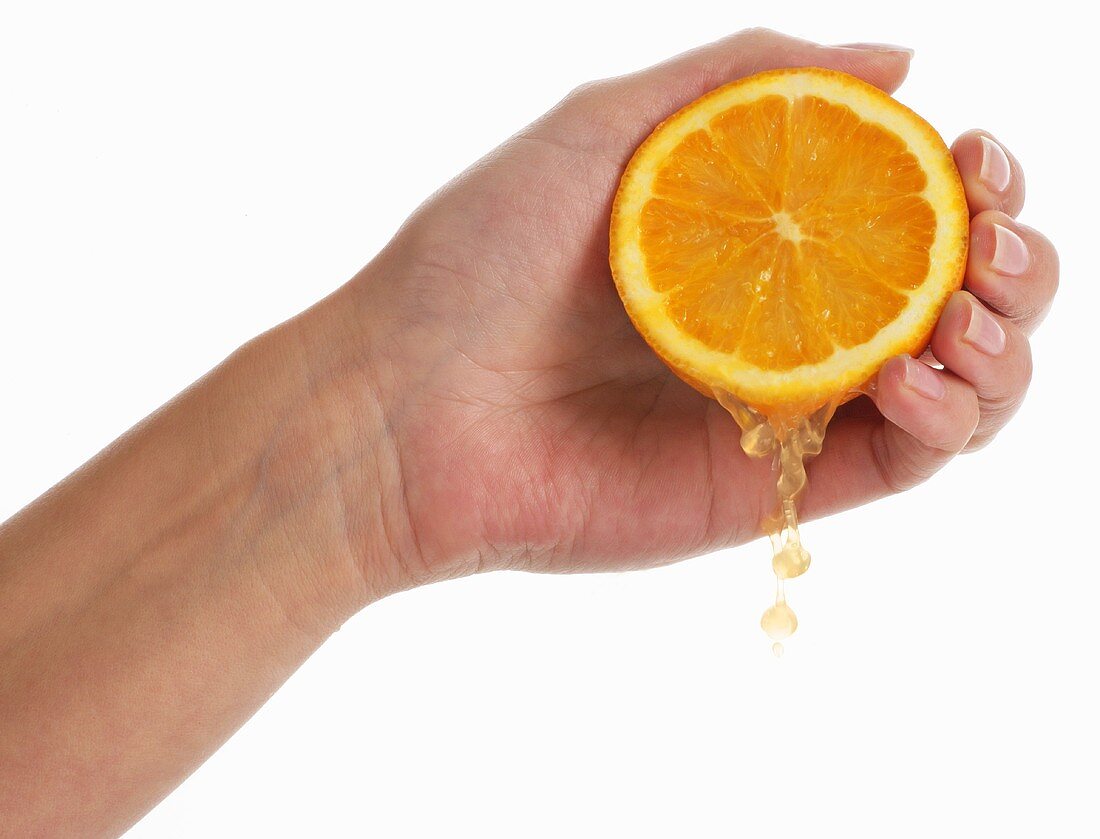 Frauenhand zerdrückt eine Orange